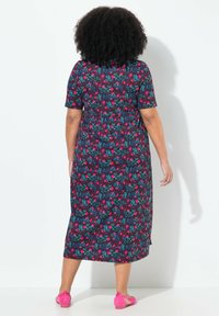 Kukallinen polvipituinen mekko tummassa kankaassa, jossa on lyhyet hihat. Mekossa on värikkäitä vaaleanpunaisia ja sinisiä kukkia mustalla taustalla.