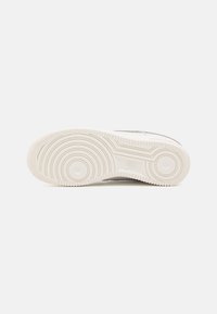 Nike sneakers met een textuur van wit rubberen zool, voorzien van concentrische cirkelpatronen en een klein logo dat near de hak is geperst.