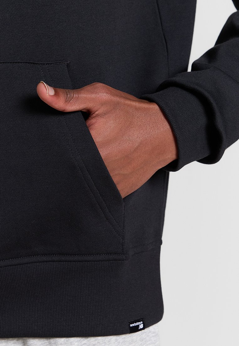 Schwarzer Sweatshirt mit einer Fronttasche, gerippten Bündchen und Saum; besitzt einen strukturierten Stoff und ein kleines Markenetikett am Saum.