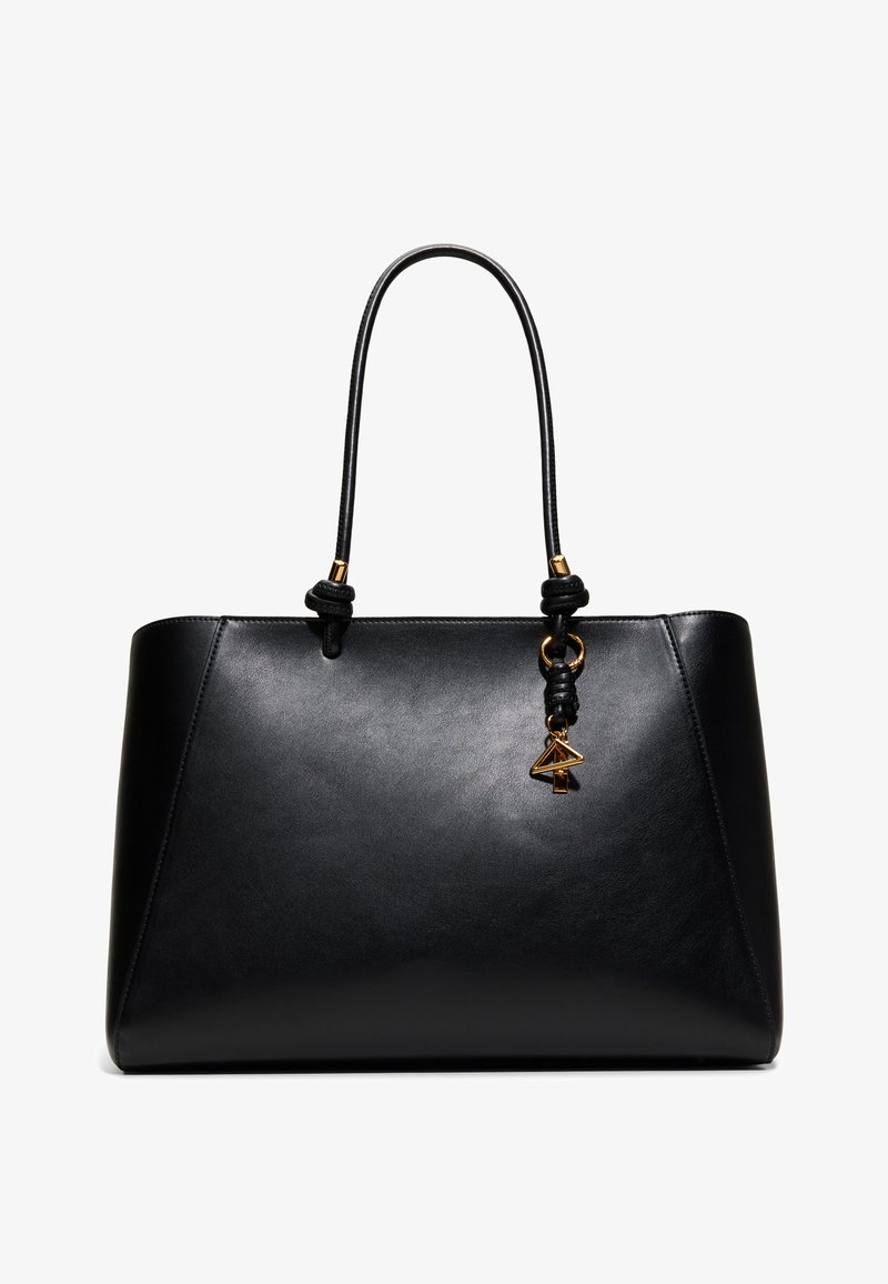 Sac à main en cuir noir avec doubles anses et breloque géométrique dorée suspendue à une anse, design minimaliste et élégant.