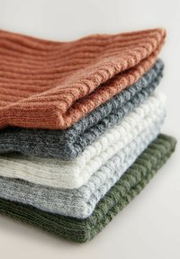 Pila di cinque accessori lavorati a maglia in vari colori: ruggine, grigio scuro, bianco, grigio chiaro e verde oliva, con una texture a coste.