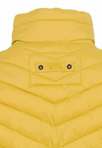 Veste matelassée jaune vue de dos avec col montant et étiquette cousue "camel active" avec deux œillets métalliques sous le col.