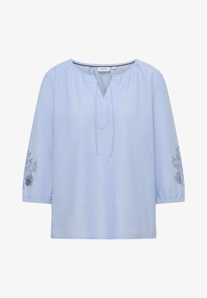 Blouse bleu clair à manches longues avec col rond froncé, fente en V avec liens, et broderie marine foncée sur les manches.