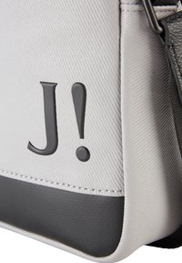 Borsa bianca texturizzata con un pannello inferiore nero, logo "J!" impressa, e design minimalista con cuciture rinforzate e rifiniture in hardware.