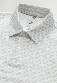 Lysegrå polo skjorte med et diskret mønster over hele stoffet, knap-eller, to knapper og et mærketiket indvendigt på kraven.