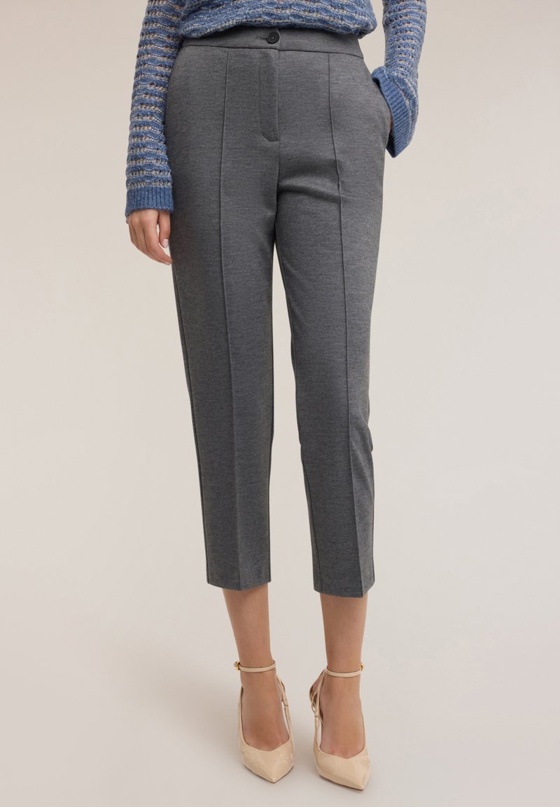 Szare spodnie w kant z gładkiej tkaniny, z przodem zapinanym na guzik i bocznymi kieszeniami, zestawione z be�żowymi szpilkami.