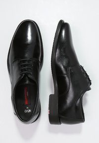 Black leather dress shoes featuring a smooth finish, lace-up design, and a textured sole; includes a red accent near the heel.