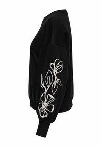 Melna kapuca ar pārmērīgu piegriezumu, kurai pa kreisi uz piedurknes ir balta ziedu izšuvuma detaļa. Ribu aproces un kakla izgriezums, maiga tekstūra.