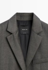 Grey blazer featuring a classic lapel design, textured fabric, and a single chest pocket. Label reads "Massimo Dutti," made in Portugal.