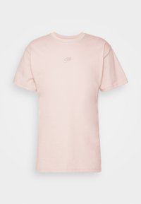 Ljusrosa bomull T-shirt med korta ärmar, rund halsringning och en liten broderad Nike-logga på bröstet. Slät textur och klassisk passform.