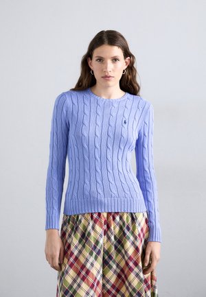 Lichtblauwe cable-knit trui met een ronde hals en geribbelde zoom, gecombineerd met een geruite, meerkleurige rok.