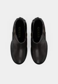 Bottines en cuir noir avec une finition lisse, présentant un inlay latéral à motif, des panneaux élastiques et un design à bout rond.