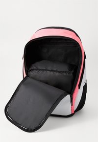 Mochila aberta com seções em rosa, preto e branco, mostrando um grande compartimento principal e um bolso de malha com fecho dentro.