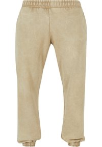 Beige joggebukser laget av mykt stoff, med elastisk midje og mansjetter, med en glatt tekstur og avslappet passform.