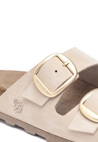 Sandalo slide in suede beige con due fibbie regolabili in tonalità oro, marchio inciso e soletta testurizzata. Suola in sughero leggera per il massimo comfort.