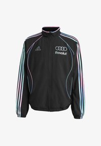 Chaqueta deportiva negra de Adidas con rayas azul pastel y rosa en las mangas, cremallera delante y logos de Revolut y Audi en el pecho.