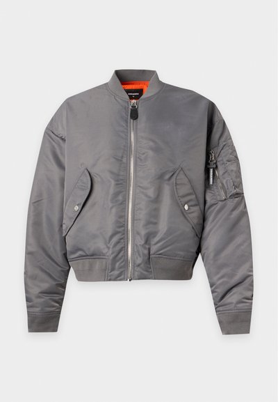 Veste bomber grise avec fermeture éclair frontale, deux poches à rabat boutonnées, poignets côtelés et doublure intérieure orange, présentée à plat sur fond blanc.