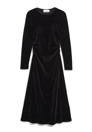 Zwarte fluwelen jurk met lange mouwen, een ronde halslijn en subtiele draperingen bij de taille. Uitlopende zoom met een gladde textuur.