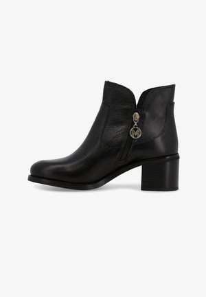 Stivaletto in pelle nera con punta arrotondata, cerniera laterale e tacco spesso. Presenta un piccolo accento metallico con logo vicino alla cerniera.