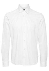 Chemise blanche à manches longues avec boutons sur le devant et col pointu, présentée sur un fond uni.