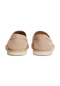 Μπεζ σουέτ παπούτσια με στρογγυλεμένο μύτη, χαμηλή κοπή και ελαφριά λαστιχένια σόλα. Διαθέτουν ορατές ραφές κατά μήκος της άκρης και ομαλή υφή.