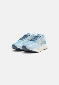 Zapatillas de running azul claro con parte superior de malla texturizada, acentos en color marino, diseño con cordones y suela blanca acolchada con dibujo de goma.
