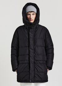 Giacca a vento nera con cappuccio, caratterizzata da un design trapuntato, zip frontale e dettagli con coulisse. La texture è liscia e leggermente riflettente.