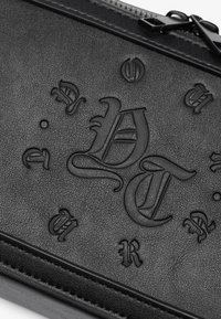 Black textured leather pouch featuring embossed letters and decorative elements, with a zip closure and flat design suitable for carry.