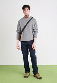 Gray sweater, navy pants, brown crossbody bag. Model wears olive-green shoes. Simple design, soft texture, and neutral colors.