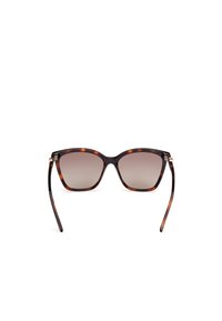 Ochelari de soare din scoică cu o formă de cat-eye, cu lentile maronii degradate și brațe negre elegante. Include accente din metal la balamale.