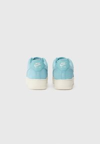 Nike Air sportcipők világoskék velúr felsőrésszel és fehér gumitalppal, hátul logóval. Simább tapintás és lekerekített forma.