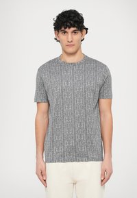 Szara koszulka z krótkim rękawem z powtarzającym się wzorem logo. Okrągły dekolt i standardowy krój. Wykonana z miękkiej tkaniny o gładkiej fakturze.