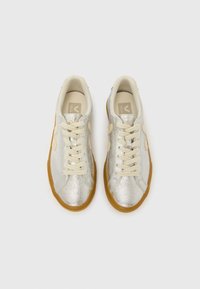 Αθλητικά παπούτσια με ασημί γκλίτερ και κρεμ λεπτομέρειες, σχέδιο με κορδόνια και μπεζ εσωτερικό. Υφή στην επιφάνεια και εξωτερική σόλα από καουτσούκ χρώματος τσίχλας.
