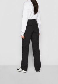 Svarta cargo-byxor med lös passform, med sidofickor och hög midja. Tillverkade av ett mjukt, strukturerat material.