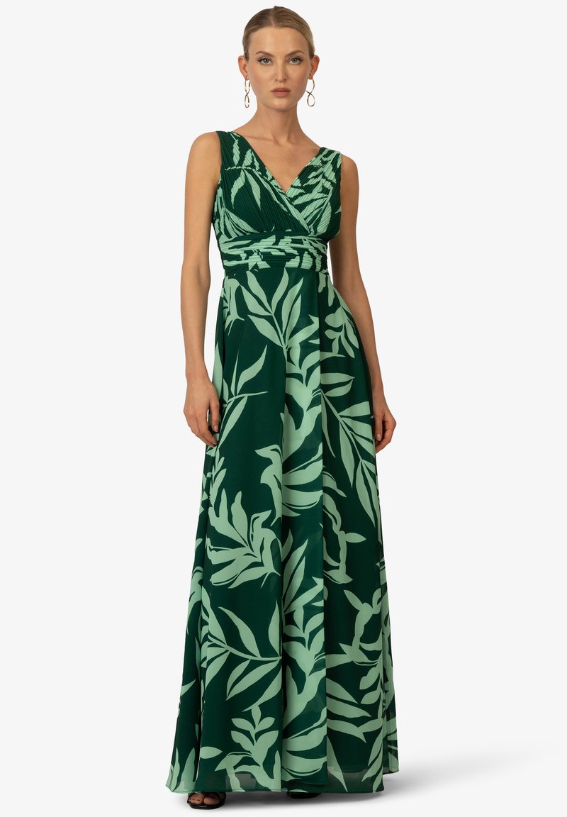 Robe maxi avec un décolleté en V et un imprimé de feuilles vertes sur fond vert foncé. Fabriquée en tissu léger avec un design fluide.