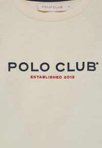 Cremefarvet sweatshirt med rund hals, der præsenterer "POLO CLUB" i marineblå og "ETABLERET 2012" i rød, fremtrædende på fronten.