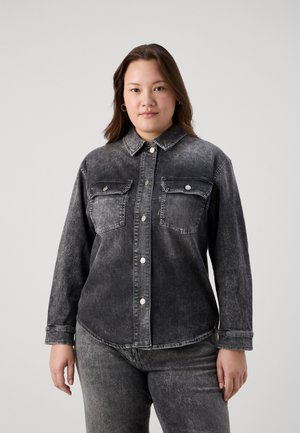 Svart denimskjorte med to brystlommer, sølvfargede trykknapper og en litt falmet tekstur, kombinert med matchende mørke jeans.