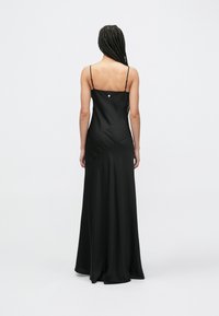 Μαύρο σατέν φόρεμα με εφαρμοστή κορσέ, λεπτές ρυθμιζόμενες τιράντες και φουσκωτή φούστα. Διαθέτει μικρή λεπτομέρεια με κουμπί στο πίσω μέρος.