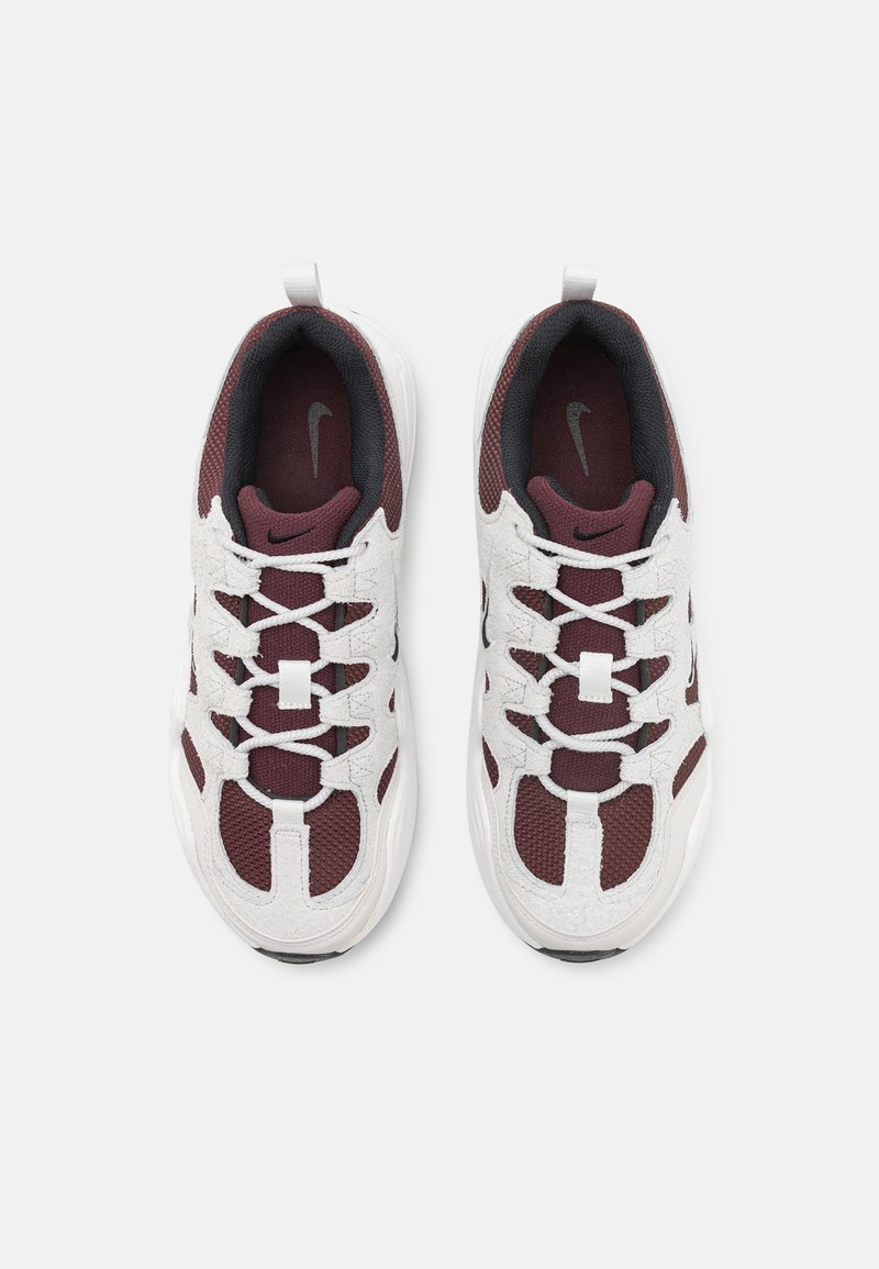 Sneakers sportivi da uomo con rete bianca, accenti bordeaux, logo nero e dettagli texturizzati. Presentano un classico design con lacci e un colletto imbottito.