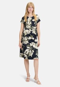 Bloemdruk jurk met een marineblauwe achtergrond, met korte mouwen, een peplum taille en een rok tot de knie, gemaakt van zachte stof.