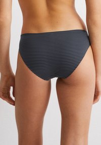 Costumi da bagno neri a righe con vita media, texture liscia e design aderente. Le righe sono sottili per un aspetto slanciato.