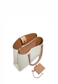 Grande borsa tote bianca con dettagli in pelle beige, dotata di una tasca interna con zip e di un portafoglio piccolo abbinato attaccato da una catena.