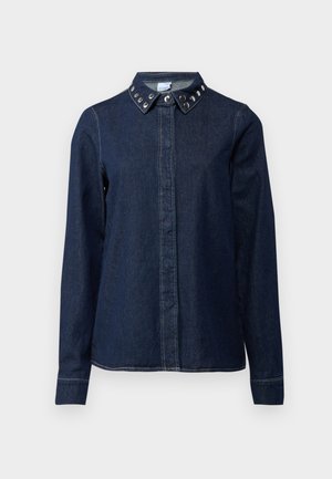Tumman denim-paita, jossa on napitus edessä, pitkät hihat ja kaulus, jossa on koristeellisia metallinastoja. Sileä tekstuuri, klassinen leikkaus.
