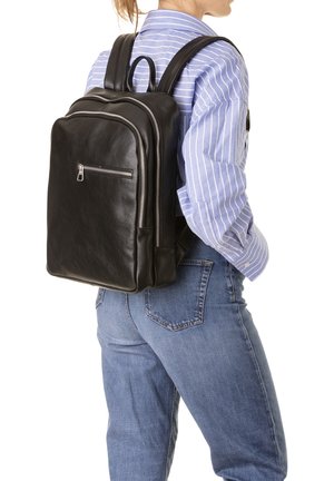Zaino in pelle nera con due scomparti con zip, spallacci regolabili e una texture liscia, indossato sulla schiena di una persona in abbigliamento casual.