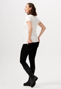 Hvid fitted t-shirt med korte ærmer, parret med sorte slim-fit bukser og høje sorte gummistøvler. Simpelt design, ingen synlige mønstre.