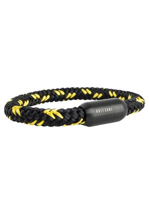 Bracelet en cordon tressé noir et jaune avec fermoir cylindrique noir portant le mot "AKITSUNE" sur un fond blanc.