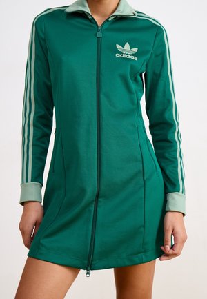 Robe zippée verte Adidas avec col et poignets vert clair, avec trois bandes vert clair sur les manches et le logo Adidas sur la poitrine.