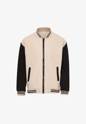 Bunda typu bomber s béžovým tělem, černými rukávy, zipovým zapínáním a proužkovaným ribbovým límcem a lemem. Obsahuje dvě přední kapsy.
