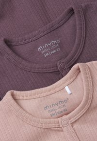 Två ribbade bebiströjor i ekologisk bomull. Den ena är mörk mauve, den andra ljus beige, båda med knappar och rund halsringning.
