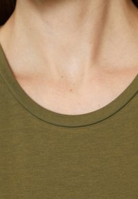 Olivgrön t-shirt med rund halsringning. Tyget ser slätt ut med en lätt glans. Inga synliga mönster eller tryck.